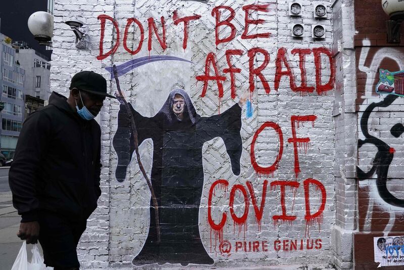 A man walks past a mural by the artist who goes by the name "Pure Genius" depicting US President Donald Trump as the Grim Reaper on a wall on Houston Street in New York City.   The latest numbers are showing coronavirus cases continued spiking in much of the United States.  AFP