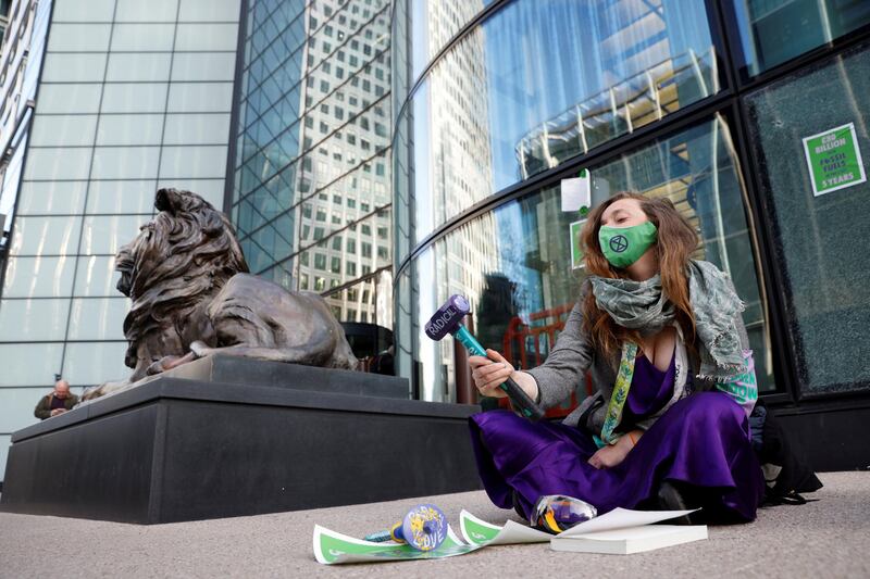An activist from the Extinction Rebellion, a global environmental movement, holds a hammer in front of a broken window during a direct action protest outside HSBC headquarters in Canary Wharf, London, Britain April 22, 2021. REUTERS/John Sibley