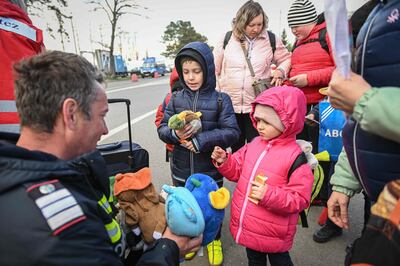 Ukrainian refugee children are given toys by a Romanian fireman after crossing the border. AFP