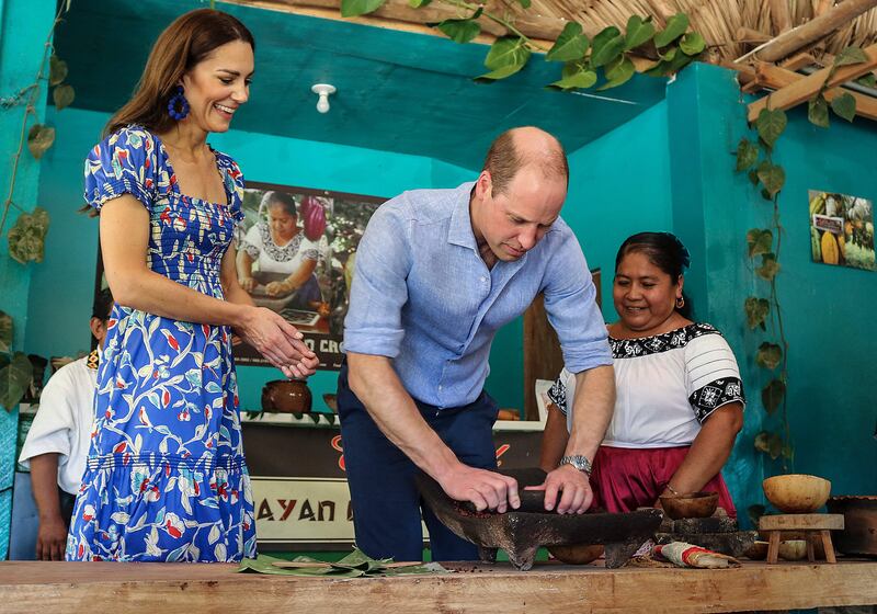 Prince William and Kate have a go at grinding cocoa. AFP