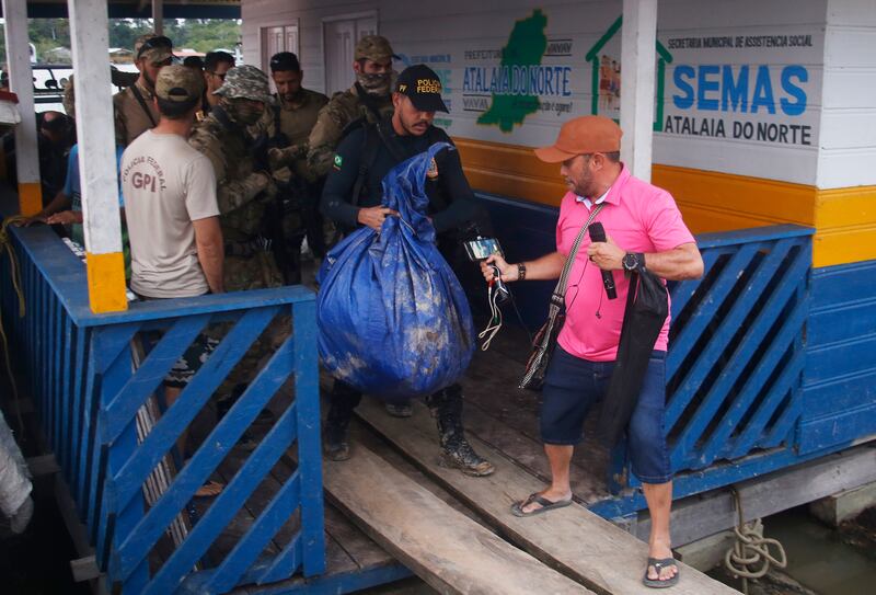 Brazilian federal police officers arrive at a pier with items found during a search for indigenous expert Bruno Pereira and British journalist Dom Phillips in Atalaia do Norte, Amazonas state, Brazil. The men have been missing for more than a week. AP