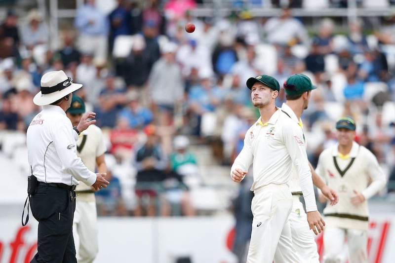 Australian fielder Cameron Bancroft (R) throws the ball to Umpire Richard Illingworth (L) during the third day of the third Test cricket match between South Africa and Australia at Newlands cricket ground on March 24, 2018 in Cape Town. / AFP PHOTO / GIANLUIGI GUERCIA