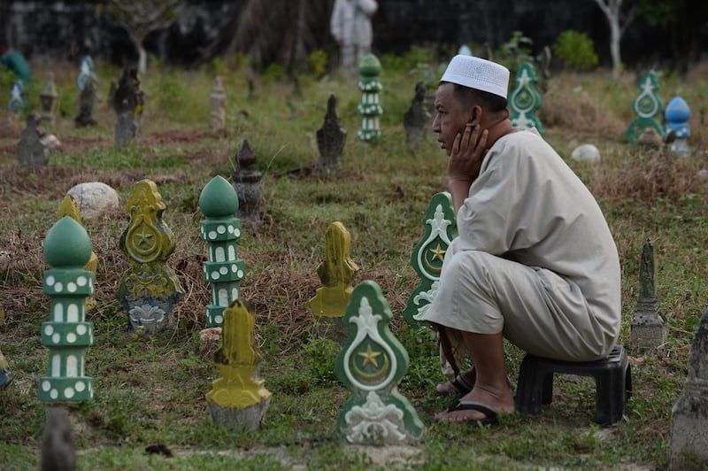 A Thai Muslim man prays before the tomb of his relatives at a cemetery during the Eid Al Adha festival in Thailand's southern province of Narathiwat. AFP