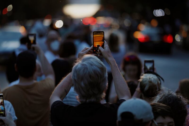 A person takes a picture as the sun sets behind buildings on 57th Street during Manhattanhenge. EPA