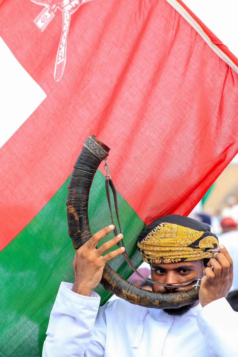 An Omani man blows a horn during celebrations, in Fanja.