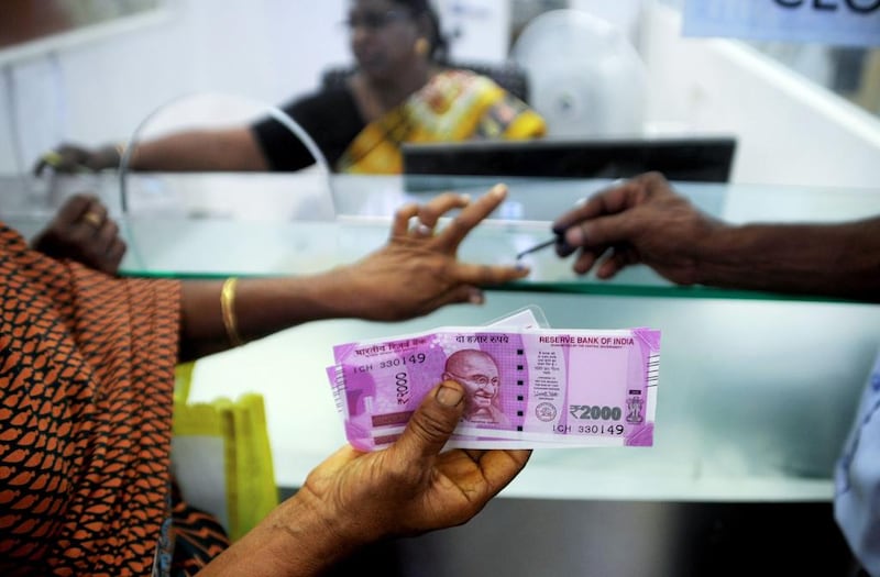 A woman displays her 2,000-rupee notes as she has her finger inked with indelible ink, after exchanging withdrawn 500- and 1000-rupee banknotes at a bank in Chennai on Thursday. India is using indelible ink to prevent people from exchanging old notes more than once, the government said last week. Arun Sankar / AFP
