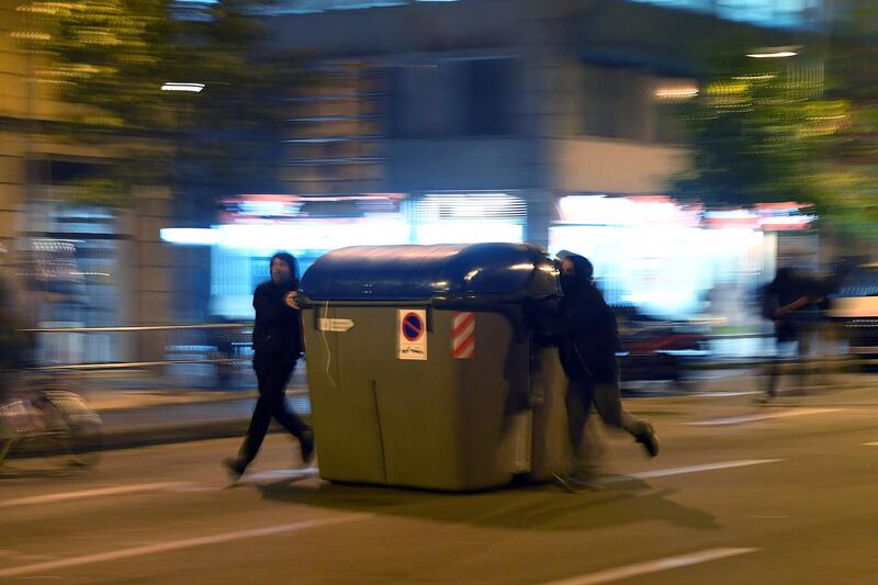 Protesters push a trash container during clashes with Catalan regional police forces. AFP