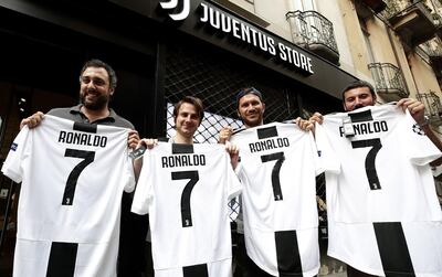 TOPSHOT - Juventus' supporters show their Cristiano Ronaldo's Juventus official Jerseys in front of the Juventus store on July 10, 2018 in Turin after Real Madrid announced today the transfer of Ronaldo to Italy's Juventus, with the Portuguese superstar saying the time had come "for a new stage" in his life. Real Madrid did not give any details as to the amount of the transfer but Spanish media reports have said it could reach 105 million euros ($120 million), with the 33-year-old signing a four-year contract worth 30 million euros per season. / AFP / Isabella Bonotto
