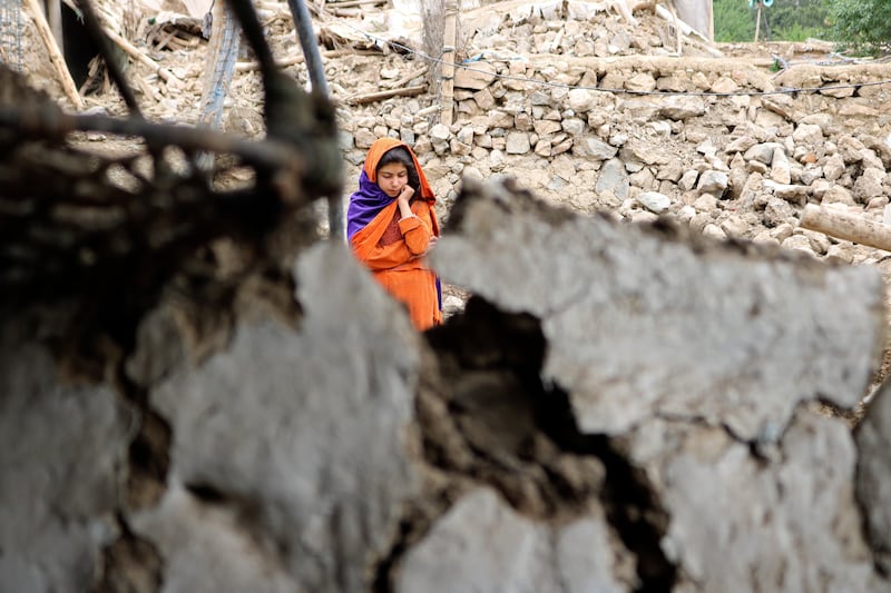 An Afghan girl stands near a house damaged by the earthquake. AP
