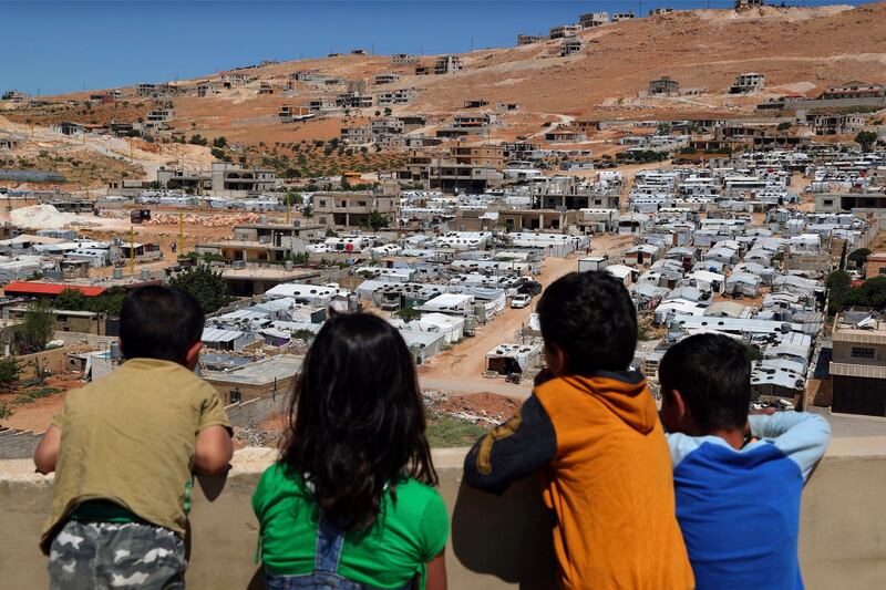 In this  photo, Lebanese children look from the rooftop of their home at a Syrian camp in the eastern Lebanese border town of Arsal, Lebanon.  AP