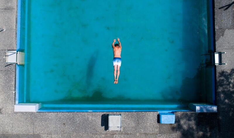 A man dives into the water at the Waldbad Ramlingen outdoor pool near Burgdorf in the Hanover region in Germany. Julian Stratenschulte / AFP