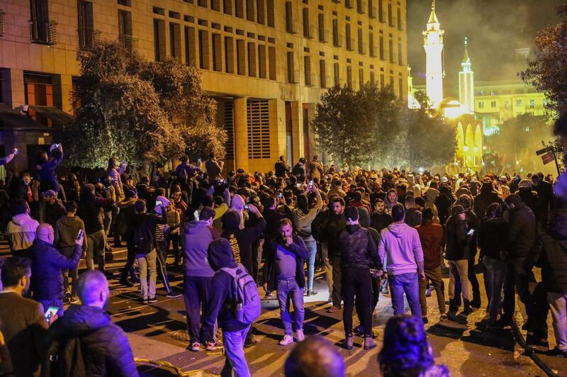 Protesters gather behind Lebanese soldiers as they flee gas grenades following stone throwing at riot police during clashes in central Beirut. EPA