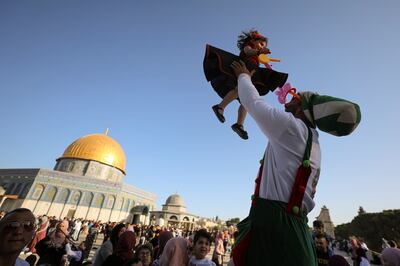 A clown lifts a young girl during Eid Al Fitr prayers at the compound that houses Al Aqsa Mosque, known to Muslims as Noble Sanctuary and to Jews as Temple Mount, in Jerusalem's Old City. Reuters