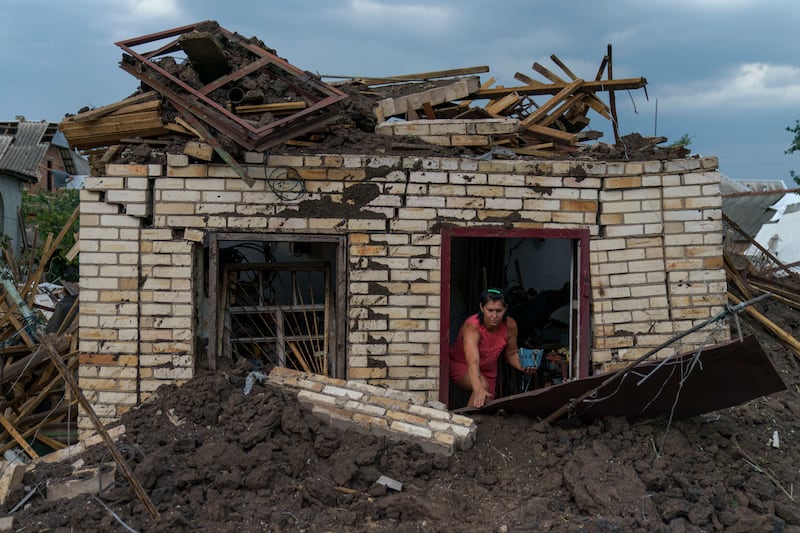 A woman recovers an item from the damaged home of her  elderly neighbour after a Russian missile strike yesterday in Druzhkivka, in Ukraine's Donetsk enclave. AP