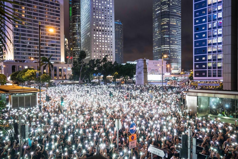 Demonstrators use smartphone flashlights during a rally organised by civil servants at Chater Garden in the Central district in Hong Kong, China. Getty
