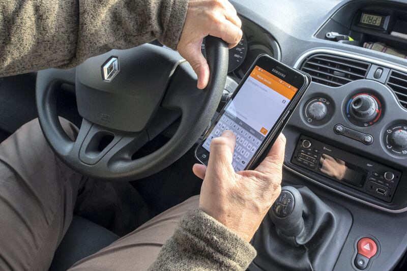 Irresponsible man at steering wheel sending message by text messaging - texting on smart phone - smartphone - cellphone while driving car on road. (Photo by: Arterra/UIG via Getty Images)