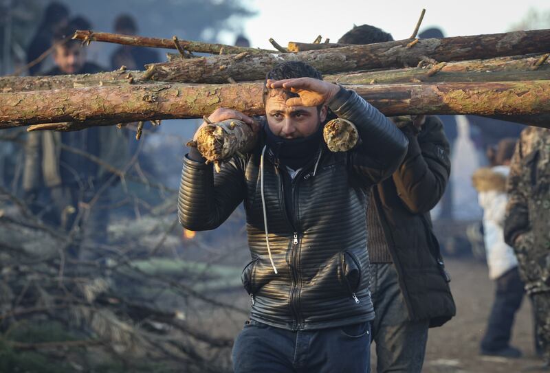 A migrant carries fire wood at the camp. EPA