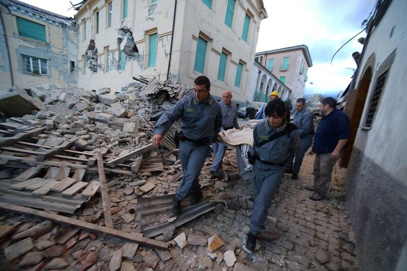 Rescuers carry a victim among damaged buildings after a strong heartquake hit Amatrice. Numerous buildings had collapsed in communities close to the epicentre of the quake near the town of Norcia in the region of Umbria. Filippo Monteforte / AFP