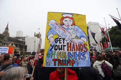 A protester holds a banner about the NHS during a demonstration against the State Visit of US President Donald Trump in central London on June 4, 2019, on the second day of Trump's three-day State Visit to the UK. US President Donald Trump turns from pomp and ceremony to politics and business on Tuesday as he meets Prime Minister Theresa May on the second day of a state visit expected to be accompanied by mass protests. / AFP / ISABEL INFANTES
