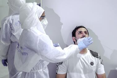A nurse conducts a nasal swab test on a UAE government employee. Victor Besa / The National.