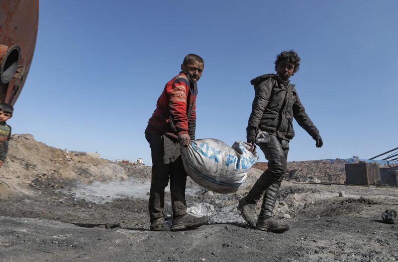 Young boys covered in black polluting residue haul a heavy sack near the Syrian village of Tarhin, in Aleppo. NGOs have sought to highlight the plight of child workers at these amateur refineries. AFP