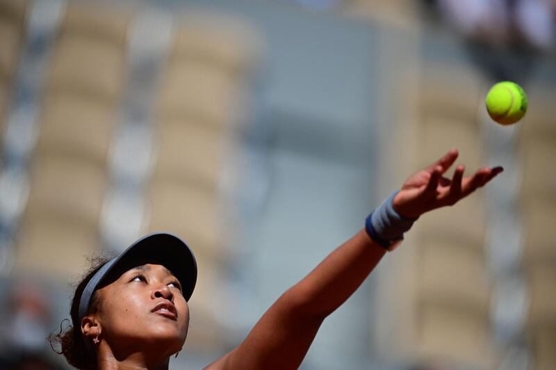 Japan's Naomi Osaka eyes the ball as she serves to Romania's Patricia Maria Tig during their women's singles first round tennis match on Day 1 of The Roland Garros 2021 French Open tennis tournament in Paris on May 30, 2021. / AFP / MARTIN BUREAU
