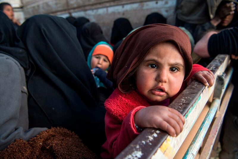Women and children fleeing from the last ISIS pocket in Syria sit in the back of a truck near Baghuz. AFP