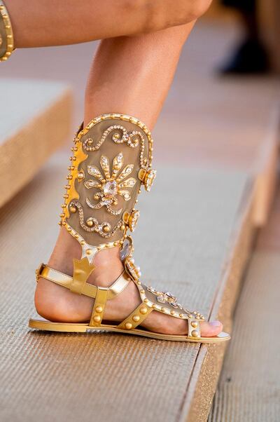 Accessories include embellished gladiator sandals, gleaming gold shields, bronze harps and clutches dotted with symmetrical coloured stones. Courtesy Dolce & Gabbana