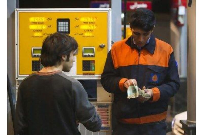 A petrol station attendant counts money as a man waits for his change in northwestern Tehran yesterday.