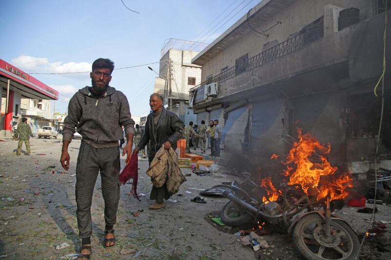 Syrians walk past a burning motorcycle. AFP