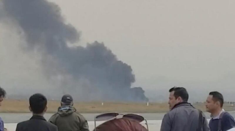 People stand as smoke rises following the crash of a Bangladeshi aircraft at Kathmandu airport. Nitin Keyal / via Reuters