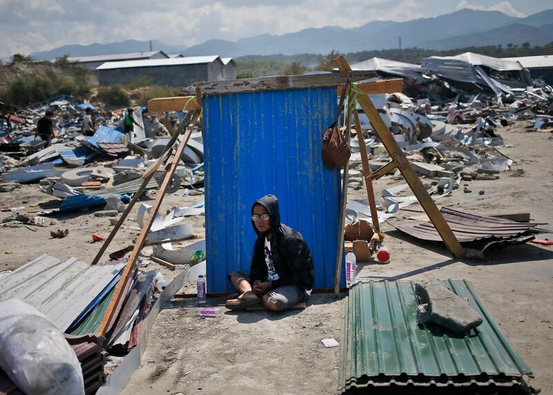 A man sits in the shade of a sheet of a corrugated tin surrounded by earthquake debris in Palu, Indonesia. Dita Alangkara/AP Photo