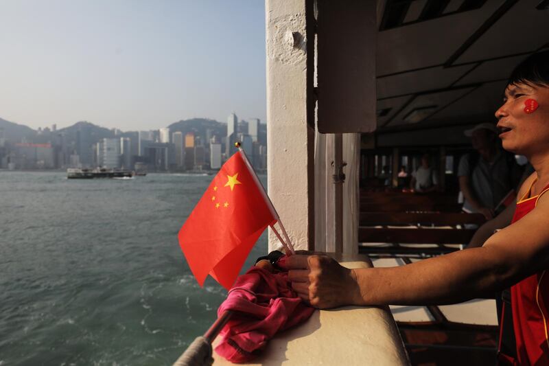 A pro-government supporter holds Chinese flags while crossing Victoria Harbour in Hong Kong. Bloomberg