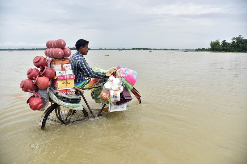An Indian vendor pushes a bicycle carrying his wares through floodwaters in Balimukh Ashigarh village in Morigoan district, in India's northeastern state of Assam. AFP / Biju Boro