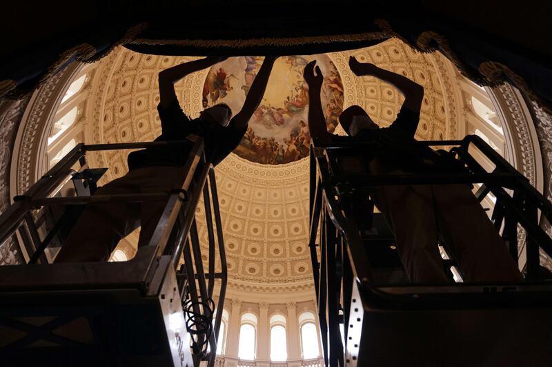 Members of the House of the Representatives Office of Chief Administrative Officer hang a drape, part of the preparation for the presidential inauguration, at the Rotunda of the US Capitol. AFP