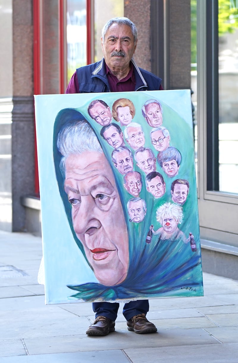 Political artist Kaya Mar with his latest painting of the queen. Getty Images