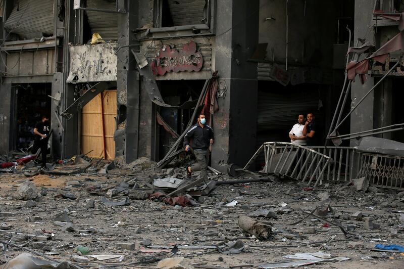 Palestinians run for cover during an Israeli air strike near the site of a tower building which was destroyed in earlier strikes in Gaza City. Reuters