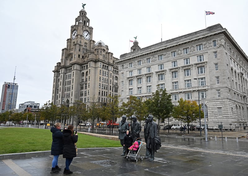 People pose with a statue of members of The Beatles, near the Liver Building in Liverpool. AFP
