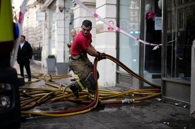 A fireman pulls hoses out of the Azagury dress store in Knightsbridge after heavy rains hit Knightsbridge, central London, on Tuesday. AP Photo / Matt Dunham