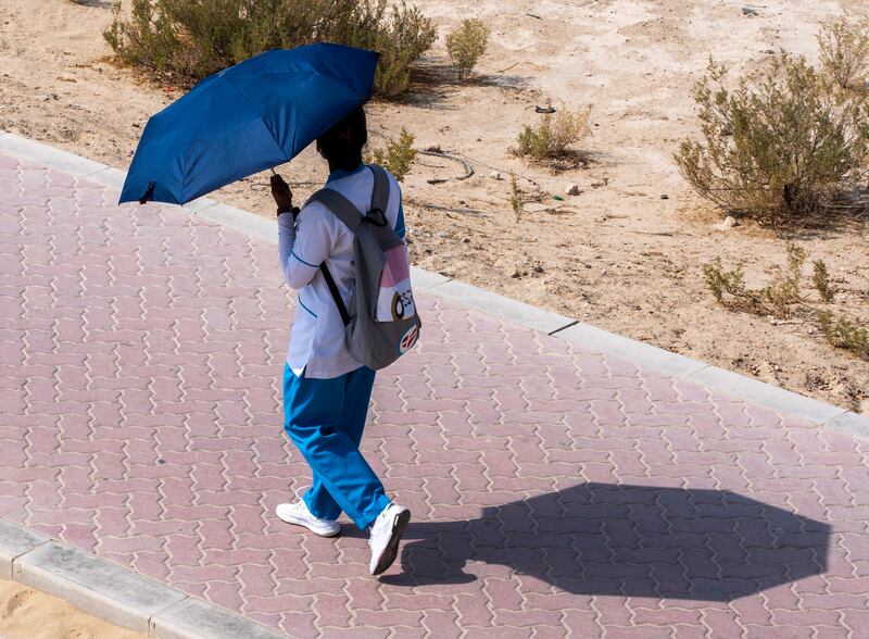 A healthcare worker uses an umbrella as shade from the sun in Abu Dhabi. All photos: Victor Besa / The National