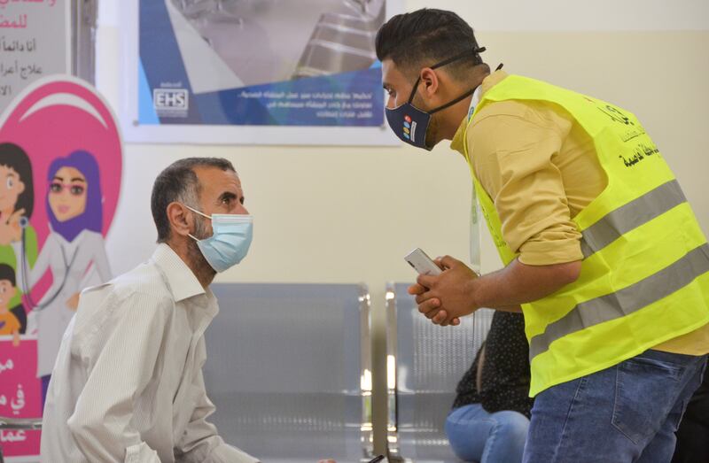 Bahaaldin Atayeh, who is encouraging people to be immunised against Covid-19, speaks to a man at a medical centre in Amman. Photo: Reuters