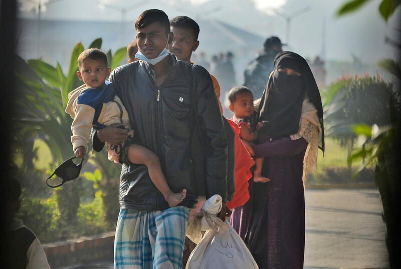 Rohingya refugees carry children and walk with their belongings to be relocated to to the island of Bhasan Char, in Chattogram, Bangladesh, Friday, Jan. 29, 2021. Authorities in Bangladesh sent a third group of Rohingya refugees to a newly developed island in the Bay of Bengal on Friday despite calls by human rights groups for a halt to the process. The government insists the relocation plan is meant to offer better living conditions while attempts to repatriate more than 1 million refugees to Myanmar would continue. (AP Photo/Azim Aunon)
