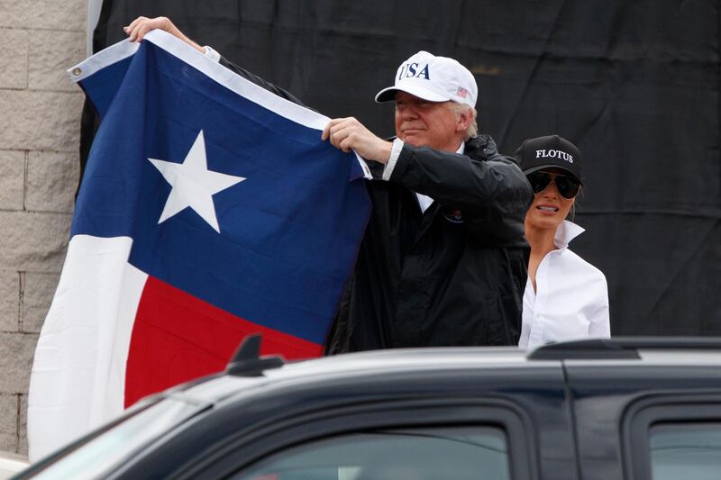 President Donald Trump, accompanied by first lady Melania Trump, holds up a Texas flag after speaking with supporters outside Firehouse 5 in Corpus Christi, Texas. Evan Vucci / AP Photo