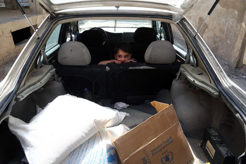 A Syrian boy sits in a car after his family received from the local council aid parcels provided by the UN World Food Programm (WFP) and the Syrian Arab Red Crescent on May 11, 2016, in the rebel-held village of Saqba, on the eastern outskirts of the capital Damascus. (Photo by AMER ALMOHIBANY / AFP)