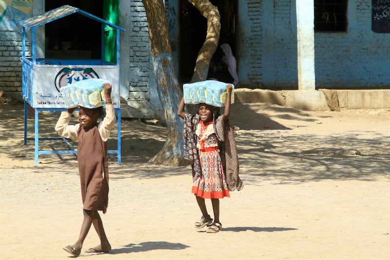 Children carry packs of humanitarian aid at a school housing people displaced by war, near the eastern city of Gedaref, Sudan. AFP