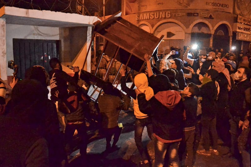 Lebanese anti-government protesters carry a security booth amid clashes with the army in the northern port city of Tripoli. AFP