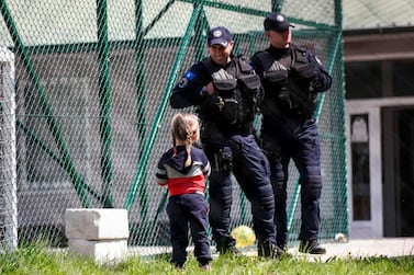 A young Kosovar child looks at Kosovar police officers as she picks up flowers in the compound of the foreign detention centre in the village of Vranidoll, Kosovo, on April 20, 2019. AFP