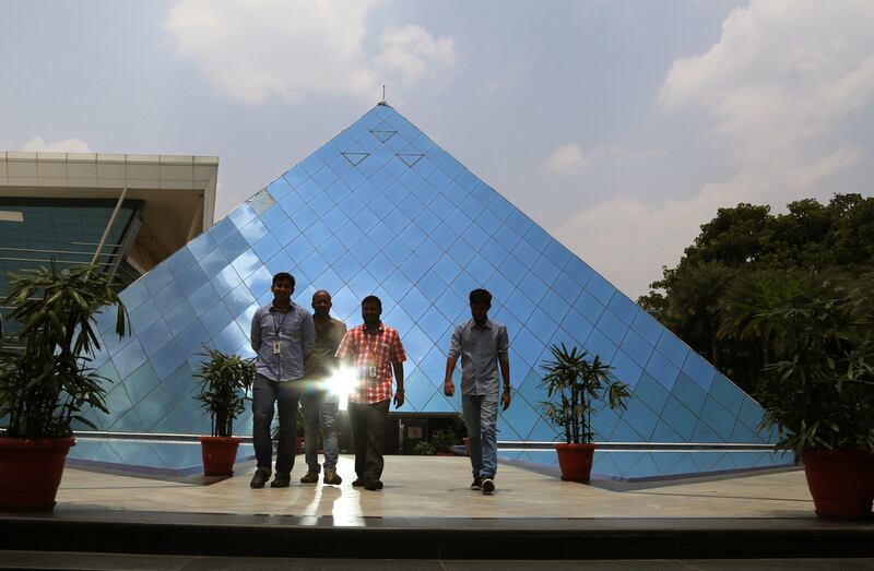 Above, Infosys employees leave a pyramid shaped building at their company’s headquarters in Bangalore. Aijaz Rahi / AP Photo