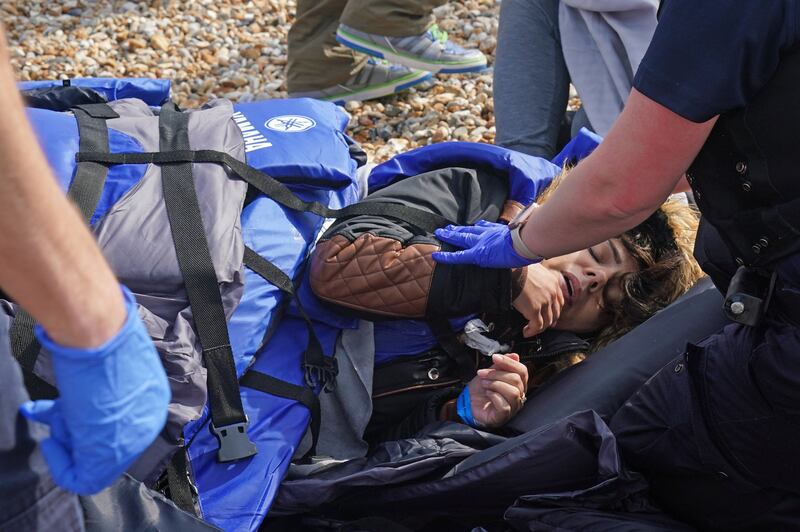 A UK immigration officer tends to a woman who has been taken ill in Dungeness. PA
