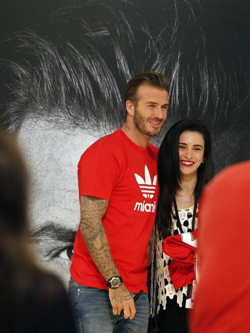 Footballing legend David Beckham smiles as he poses for a picture with a fan following his arrival at Mall of the Emirates. Karim Sahib / AFP